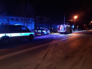 Zdjęcie wykonane nocą. Przedstawia dwa radiowozy policyjne i samochód strażacki na miejscu zdarzenia